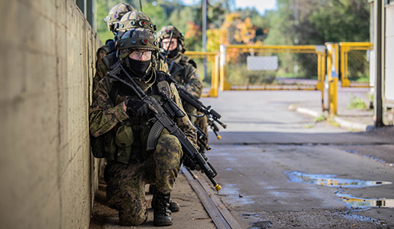 Kuvassa sotilaita vihreissä sotilasasuissa kyykkyasennossa aseet käsissään.