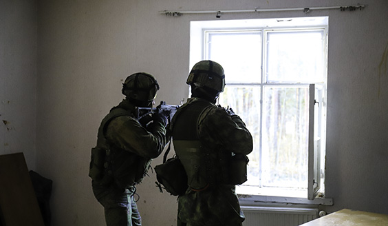 Sotilaspoliisit tähtäävät aseilla rakennuksen sisältä ulos.