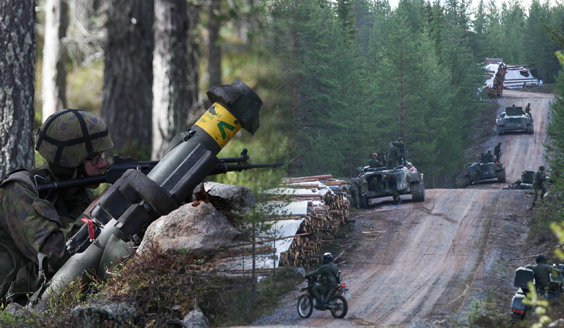 Kaksi kuvaa liitetty yhteen. Toisessa sotilas tähtää kiväärillä metsässä vieressään panssarintorjunta-ase. Toisessa maavoimien kalustoa ja sotilaita metsätiellä. 