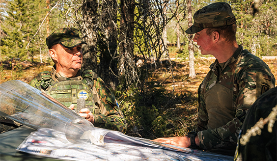 Suomalainen ja amerikkalainen sotilas tutkivat karttaa ajoneuvon konepellin päällä kesäisessä metsämaastossa.