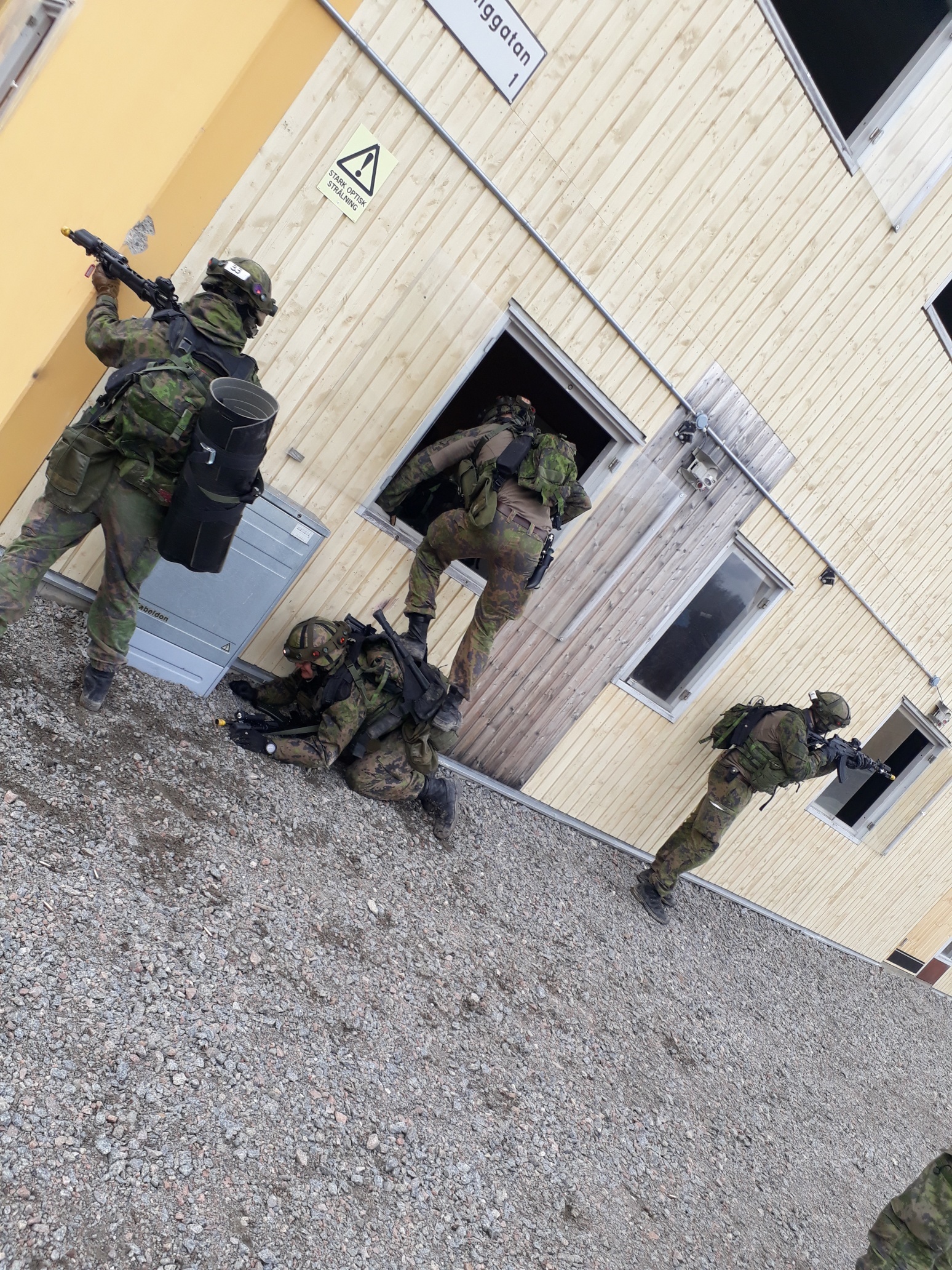 Sotilaat tähtäävät rynnäkkökivääreillä, yksi menee ikkunasta sisään. Rakennetun alueen taisteluharjoitus käynnissä.