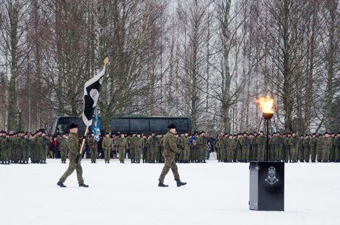 Paljon sotilaita seisoo muodossa valatilaisuudessa. Yksi sotilas kantaa lippua.
