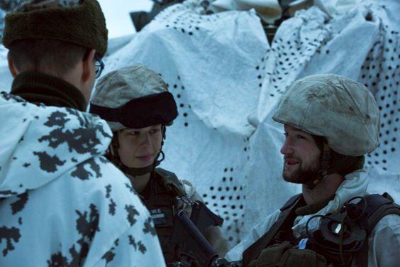 Kolme lumipukuista sotilasta juttelee
