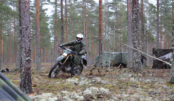 Sotilas ajaa moottoripyörällä metsässä.