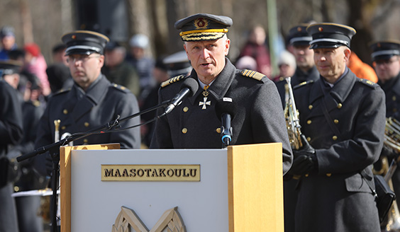 puolustusvoimain komentaja puhumassa puhujapöntössä, taustalla orkesteri