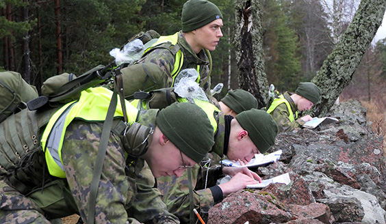 Upseerioppilaat tehtävärastilla. Yksi varusmies katsoo eteenpäin intensiivisesti ja loput neljä tutkivat karttaa.