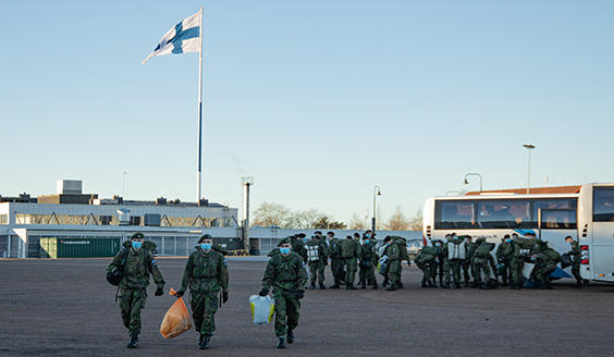 Kurssin 257 oppilaita kävelee ulos linja-autosta tavaroineen Haminan Reserviupseerikoulun varuskunta-alueella. Taustalla Suome lippu.
