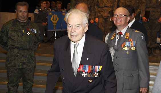 Tuomas Gerdt kävelee Reserviupseerikoulun Maneesin käytävällä takanaan sotilashenkilöitä ja upseerikokelaita.