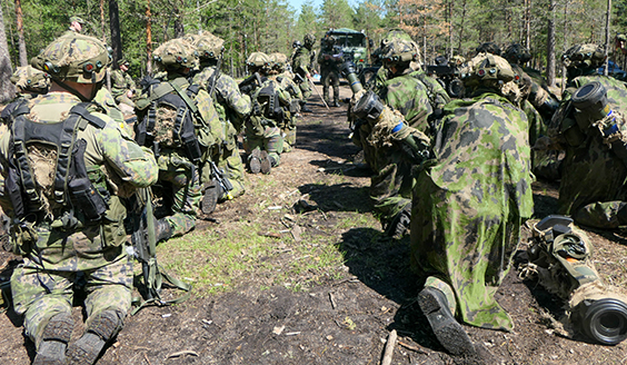 sotilaat kuuntelevat polviasennossa käskynantoa maastossa