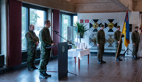 Kuvassa Porin prikaatin komentaja pitää Säkylän sotilaskodissa puhetta kotiutuville varusmiehille, taustalla prikaatin lippu.