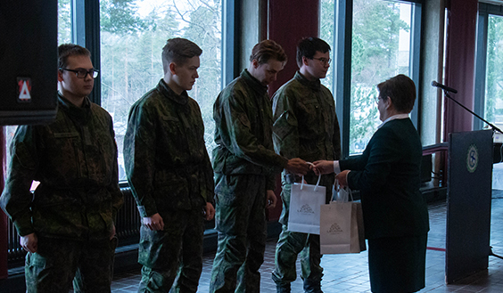 Sotilaskotisisar palkitsee Säkylän sotilaskodissa varusmiehiä, joita seisoo rivissä neljä.