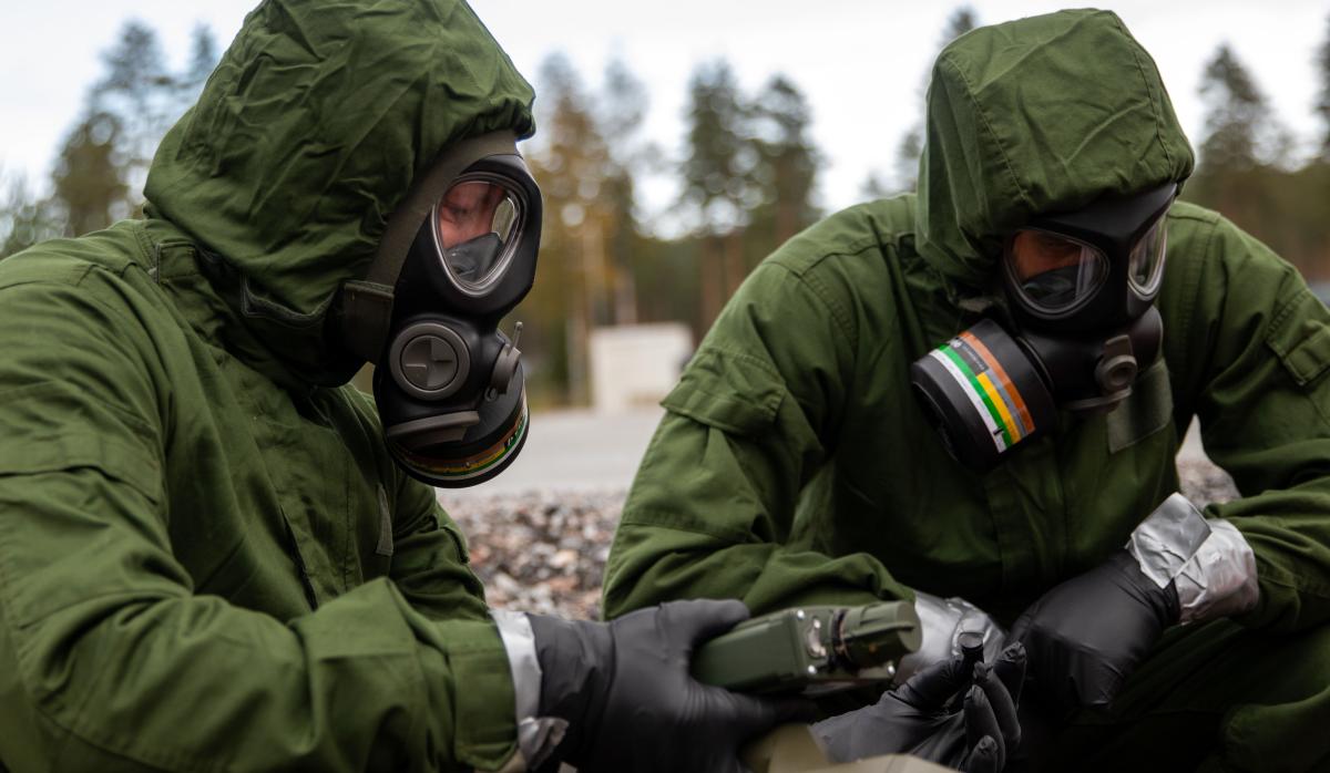 Kaksi suojavarusteisiin pukeutunutta suojelujoukkueen sotilasta harjoittelee vaarallisten aineiden tunnistamista.