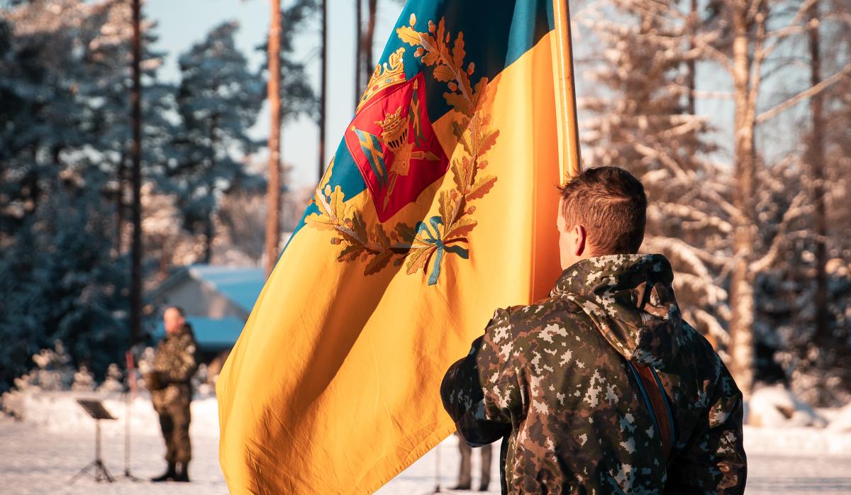 Kuvassa sotilaan pitelemä Porin prikaatin lippu talvisessa miljöössä.