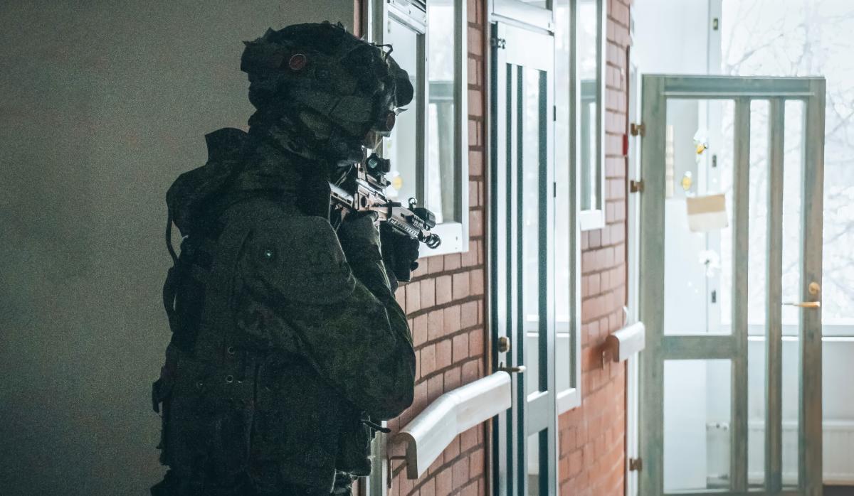 Kuvassa sotilas rakennennuksen sisätilassa varmistamassa kulmaa edessä avautuvalle käytävälle