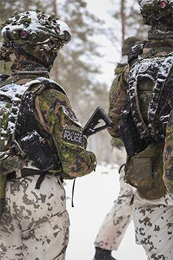 Kaksi sotilaspoliisia talvisessa maisemassa selkä kameraan päin