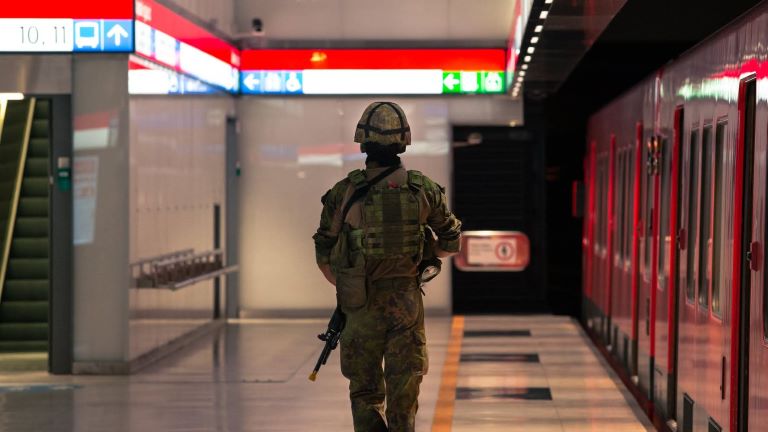 Varusmies kävelee metroasemalla poispäin kamerasta selkä kameraanpäin.