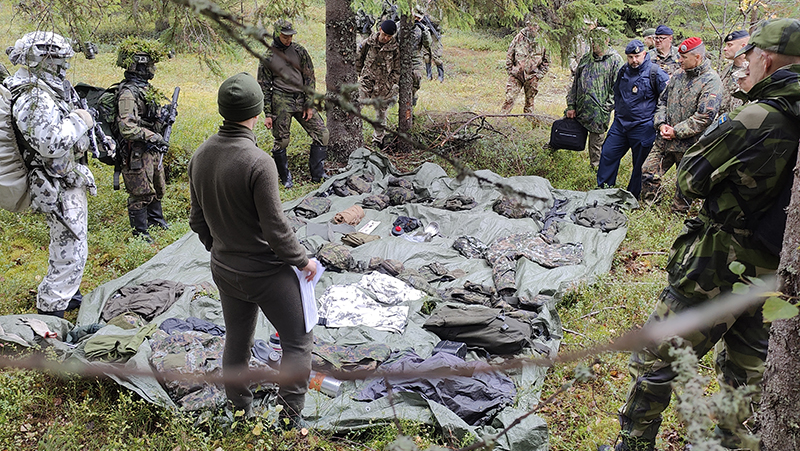 Soldiers in the forest watching the equipment demonstration.