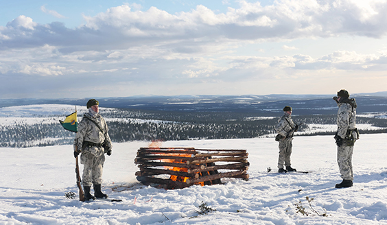 Varusmiehiä lumipuvuissa tunturin huipulla.