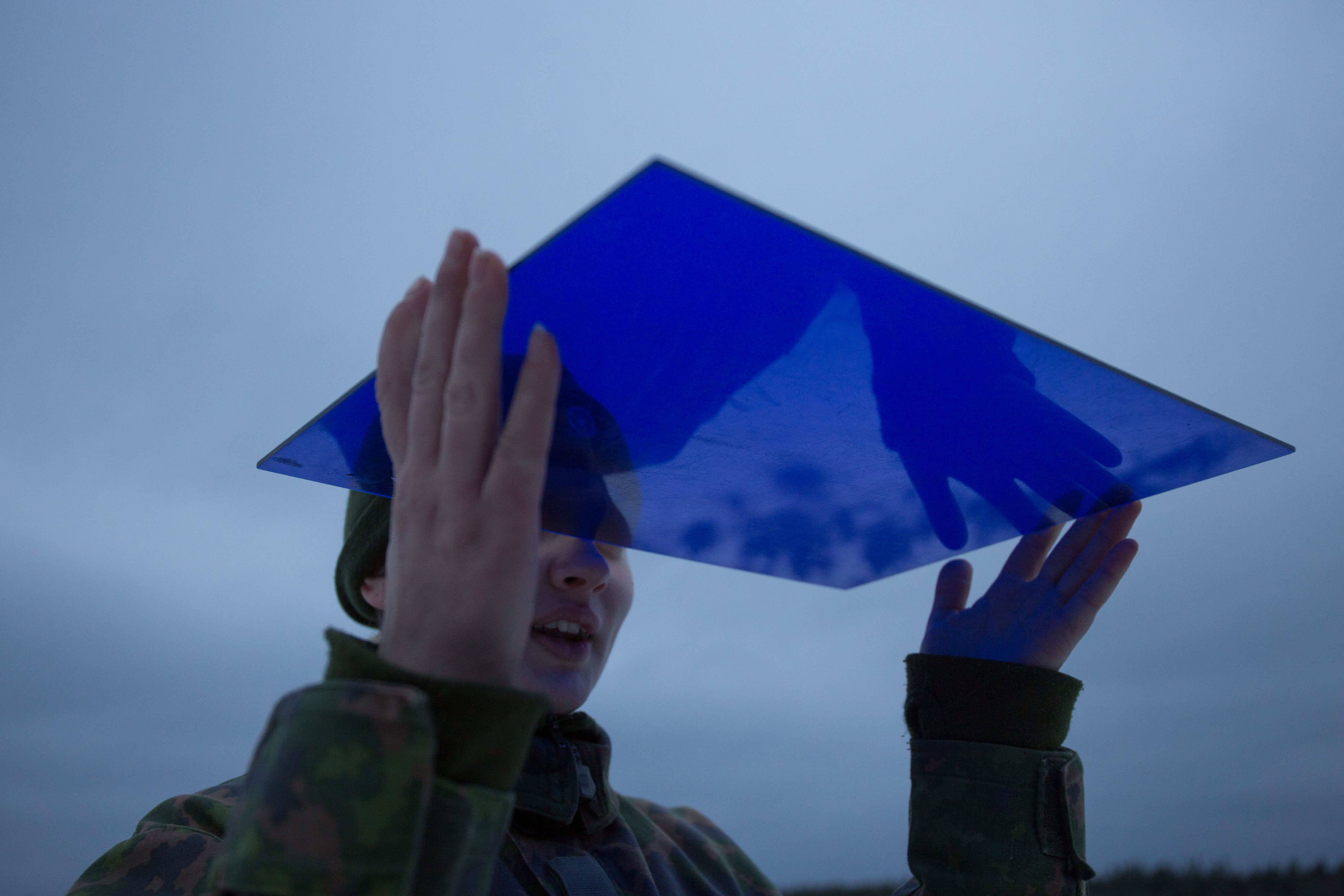 Sotilas pitää sinistä levyä ilmassa ja tarkkailee sitä