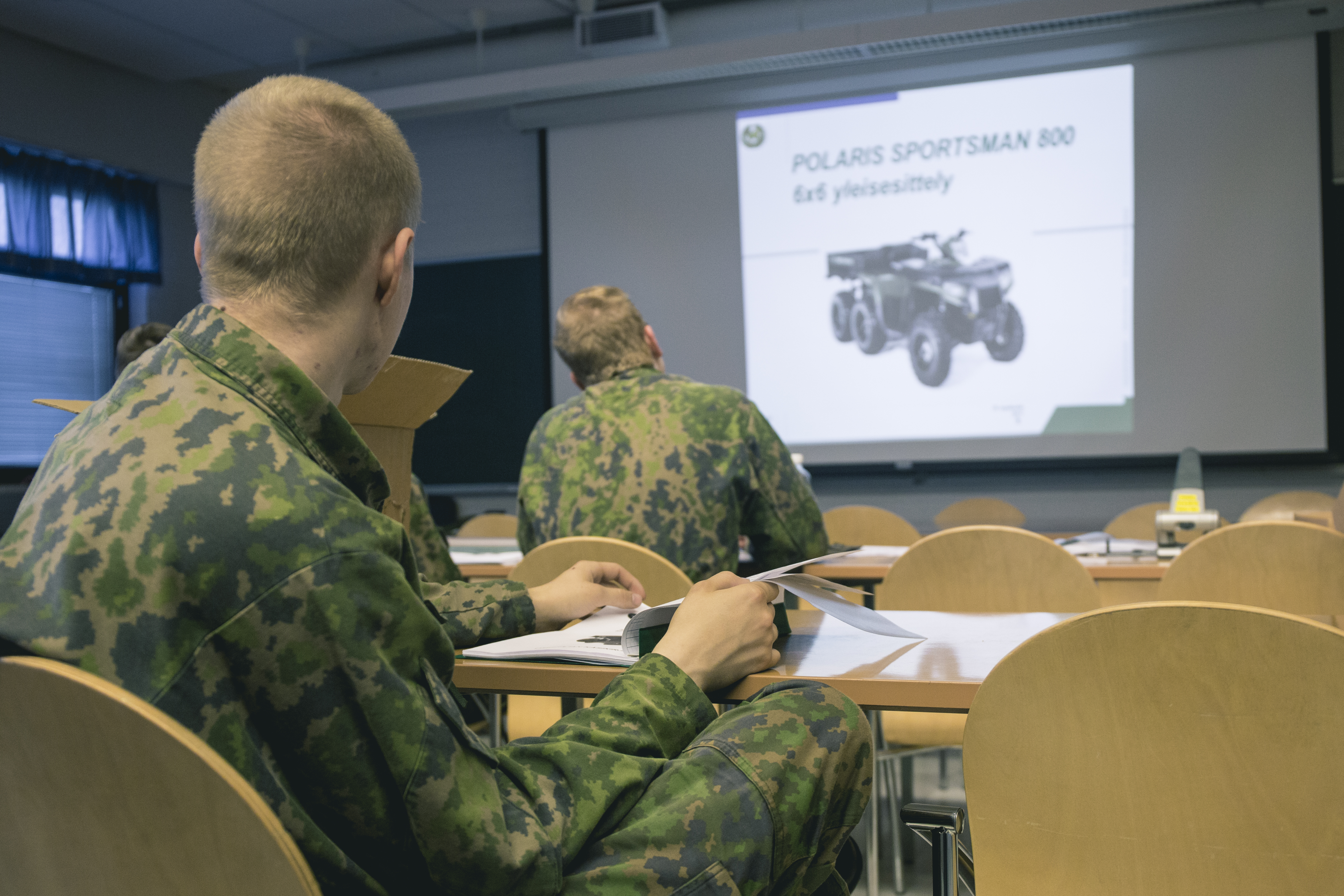 Sotilaat luokkatilassa seuraamassa opetusta. Valkokankaalla lukee Polaris Sportsman 800 yleisesittely.