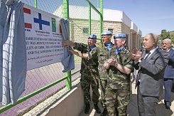 Kolme sotilasta paljastavat verhon takaa kyltin jossa on eri maiden lippuja ja tekstiä. Siviilit taputtavat.