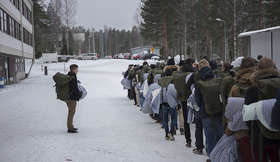 Ihmiet kävelevät jonossa kasarmilla liinavaatteiden kanssa