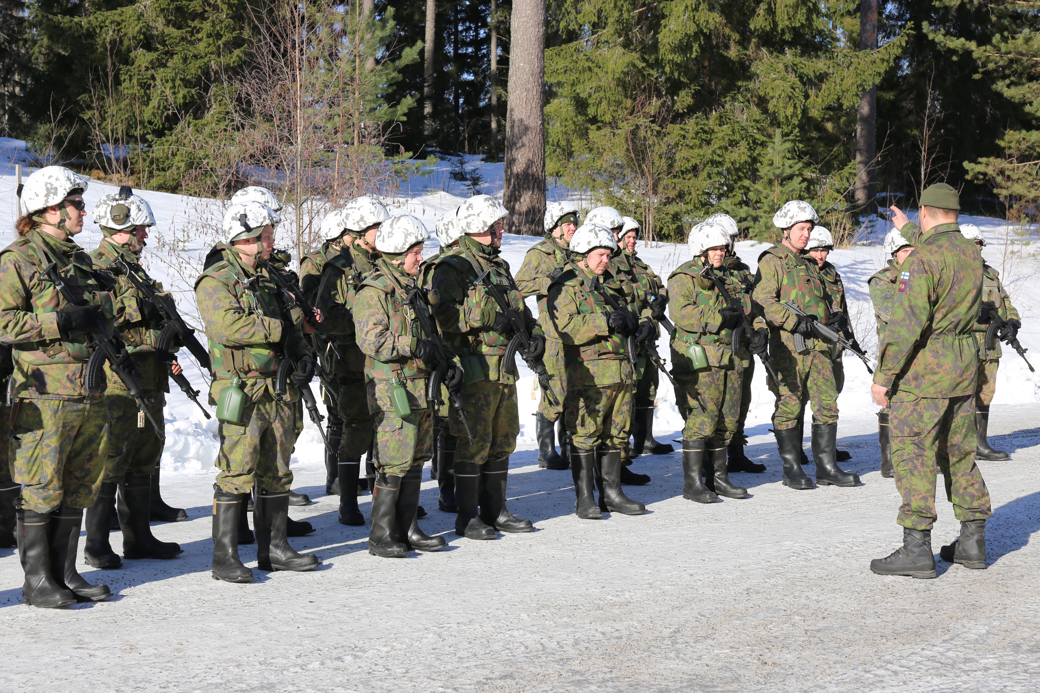 Sotilaat kuuntelevat muodossa kouluttajaa joka osoittaa metsään