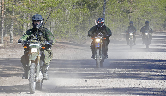 Soldiers ride motorcycles on a dirt road