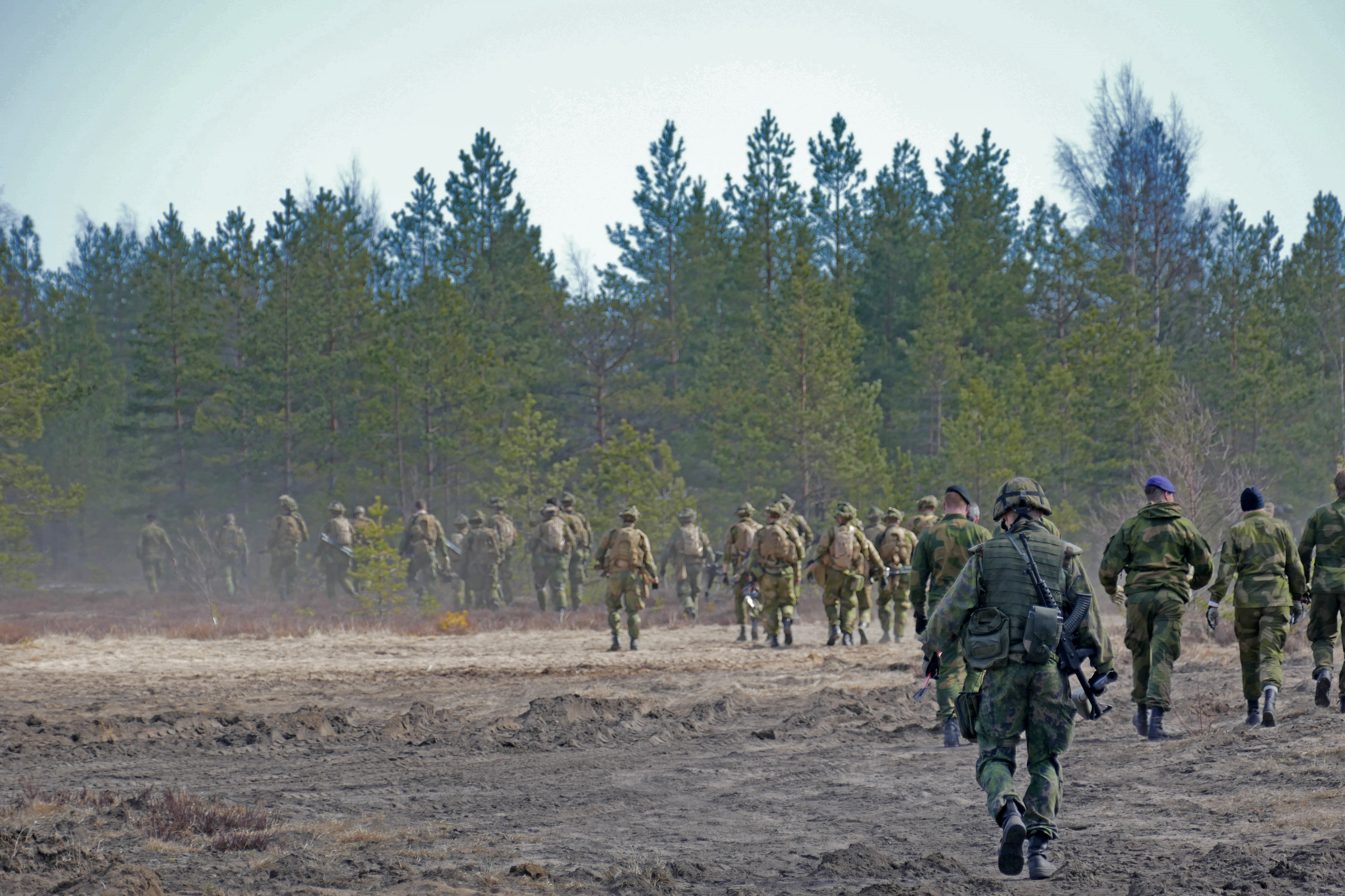 Sotilaita etenemässä hiekkakentältä metsikköön