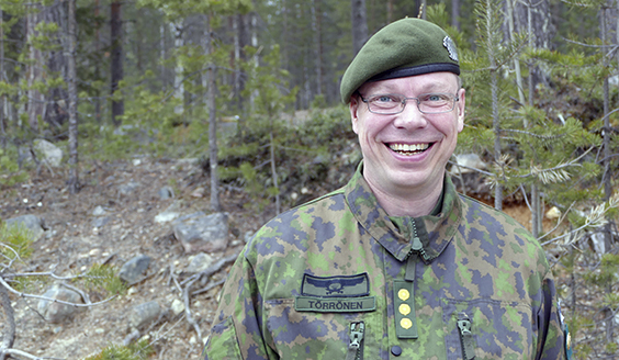 Eversti Kaarle Törrönen hymyilee maastossa