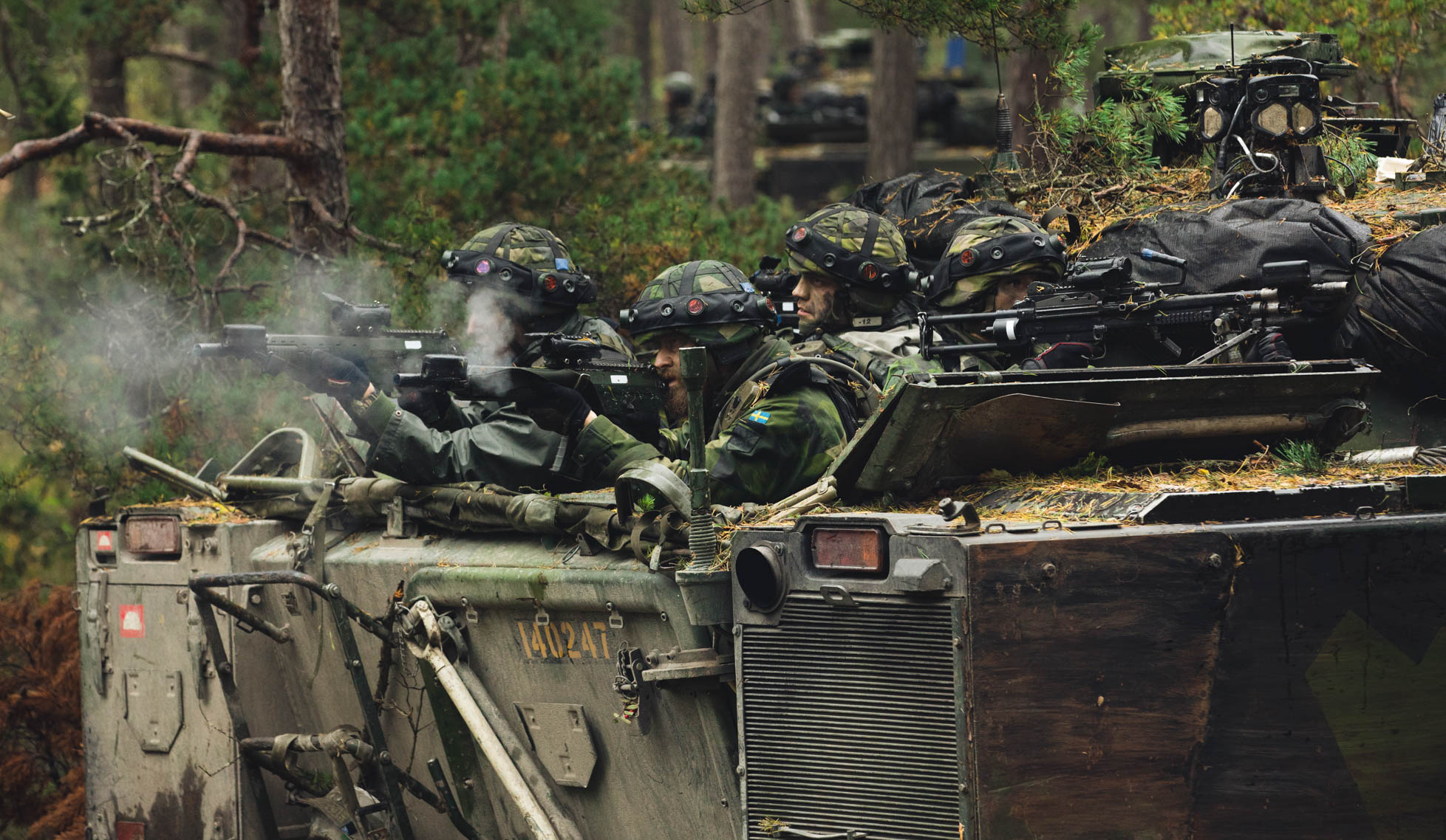 Four soldiers shooting from a tank with assault rifles and machine guns