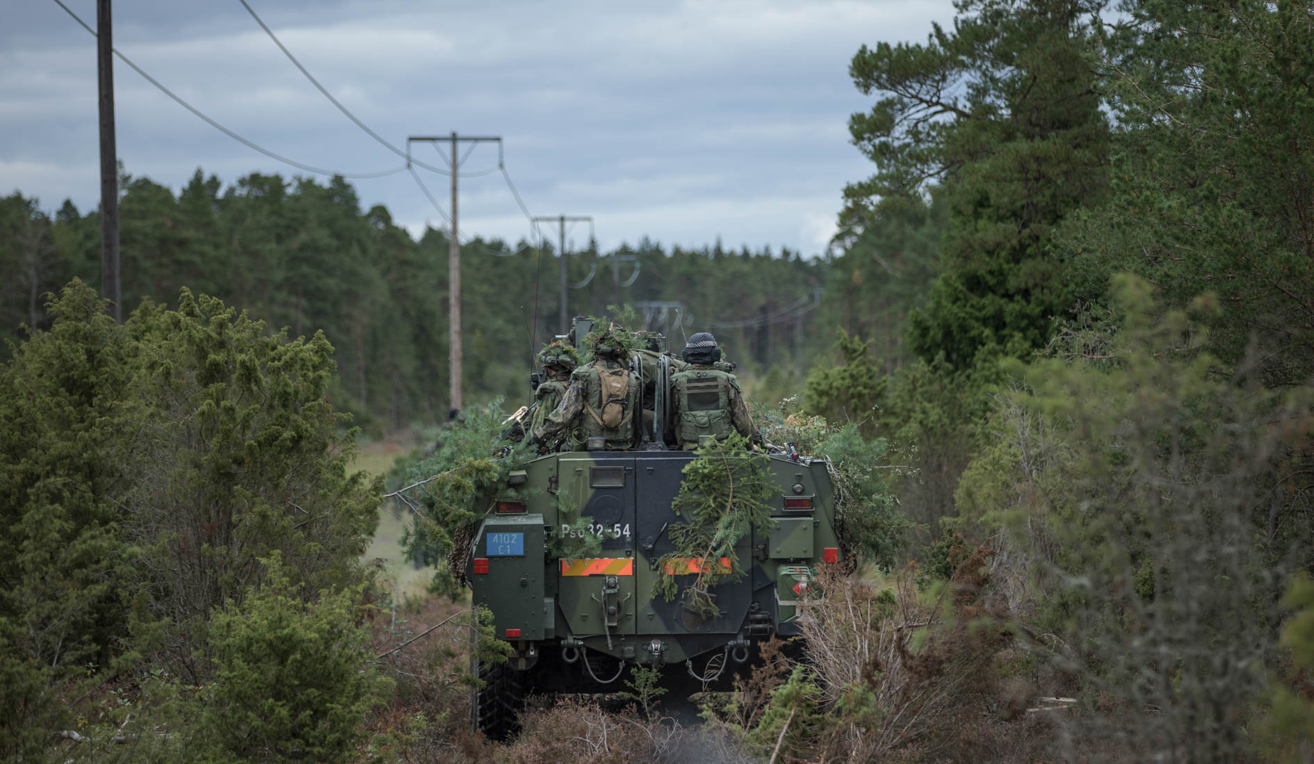 Sotilaita miehistönkuljetuspanssarivaunun kyydissä kapealla metsätiellä