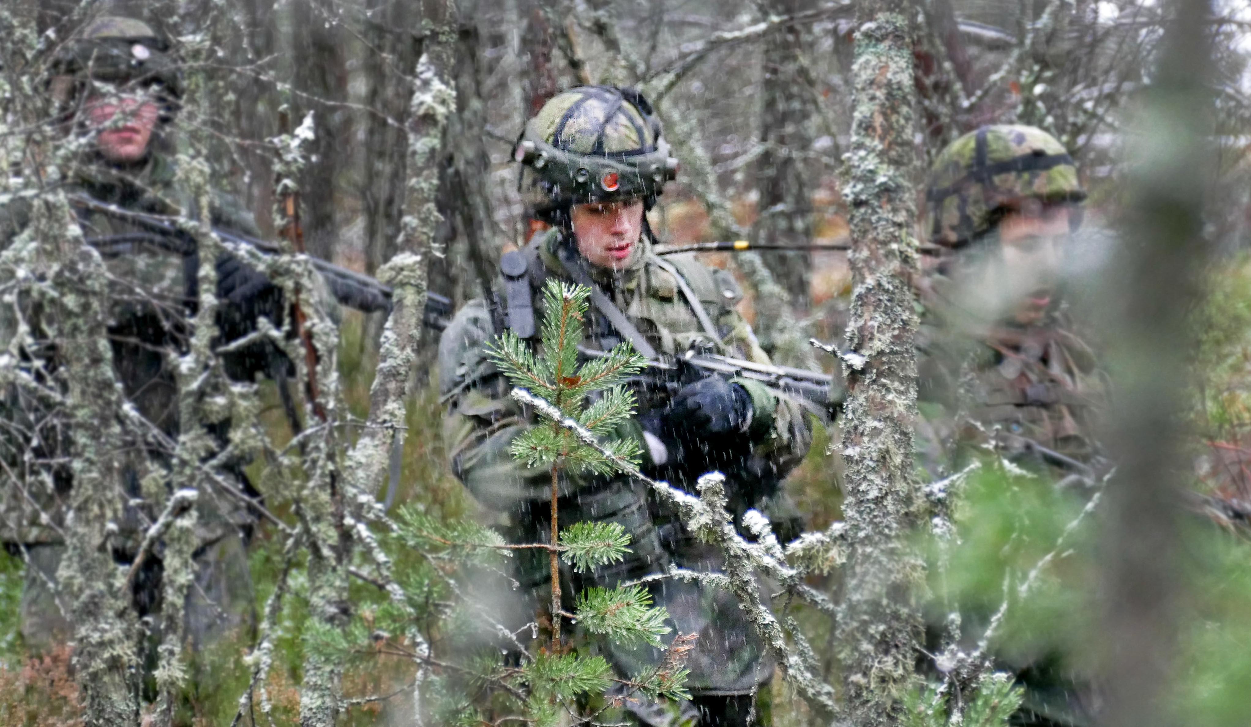 Kolme sotilasta tarpoo tiheässä metsikössä