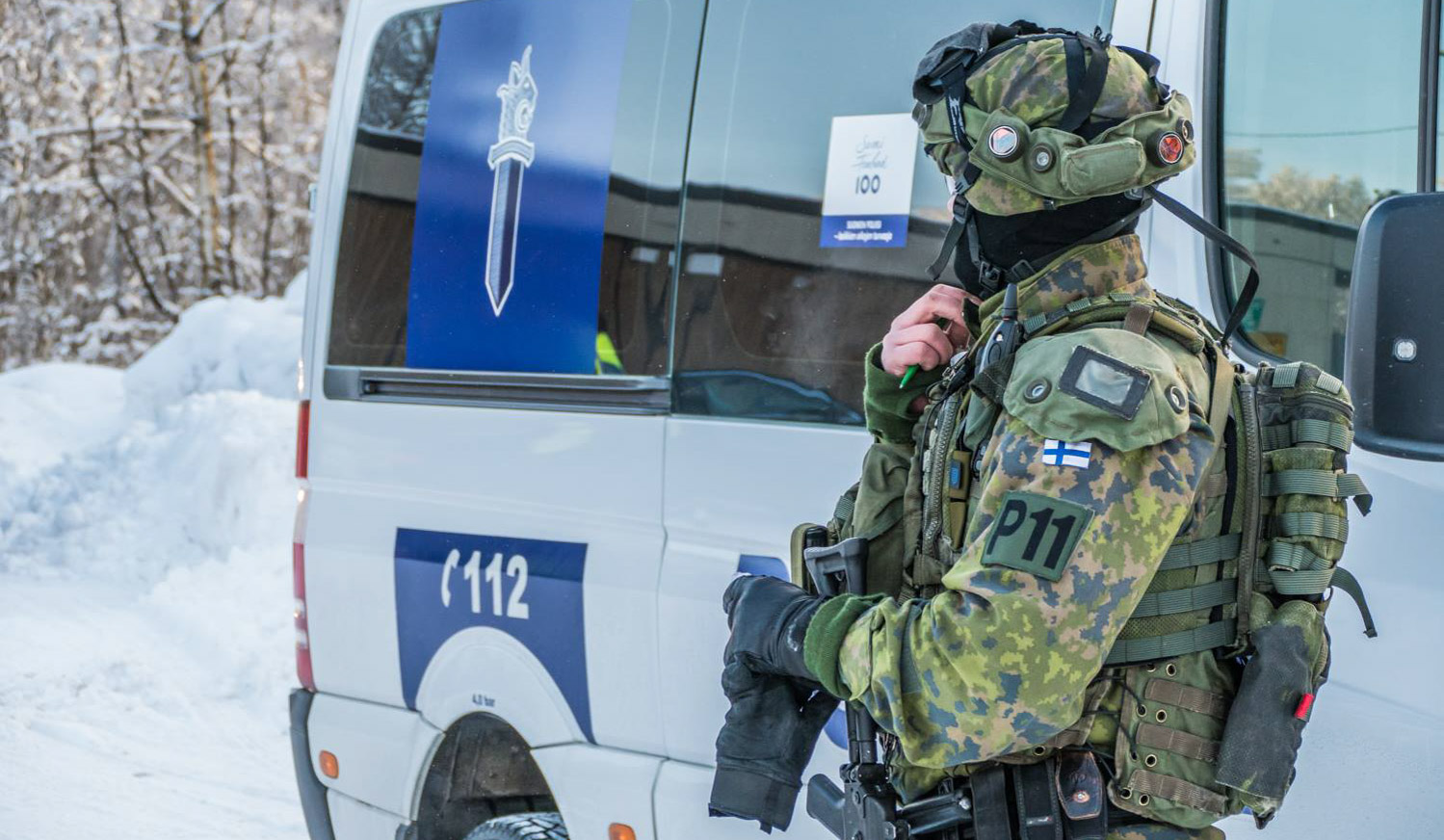 Military police in combat gear next to a police van 