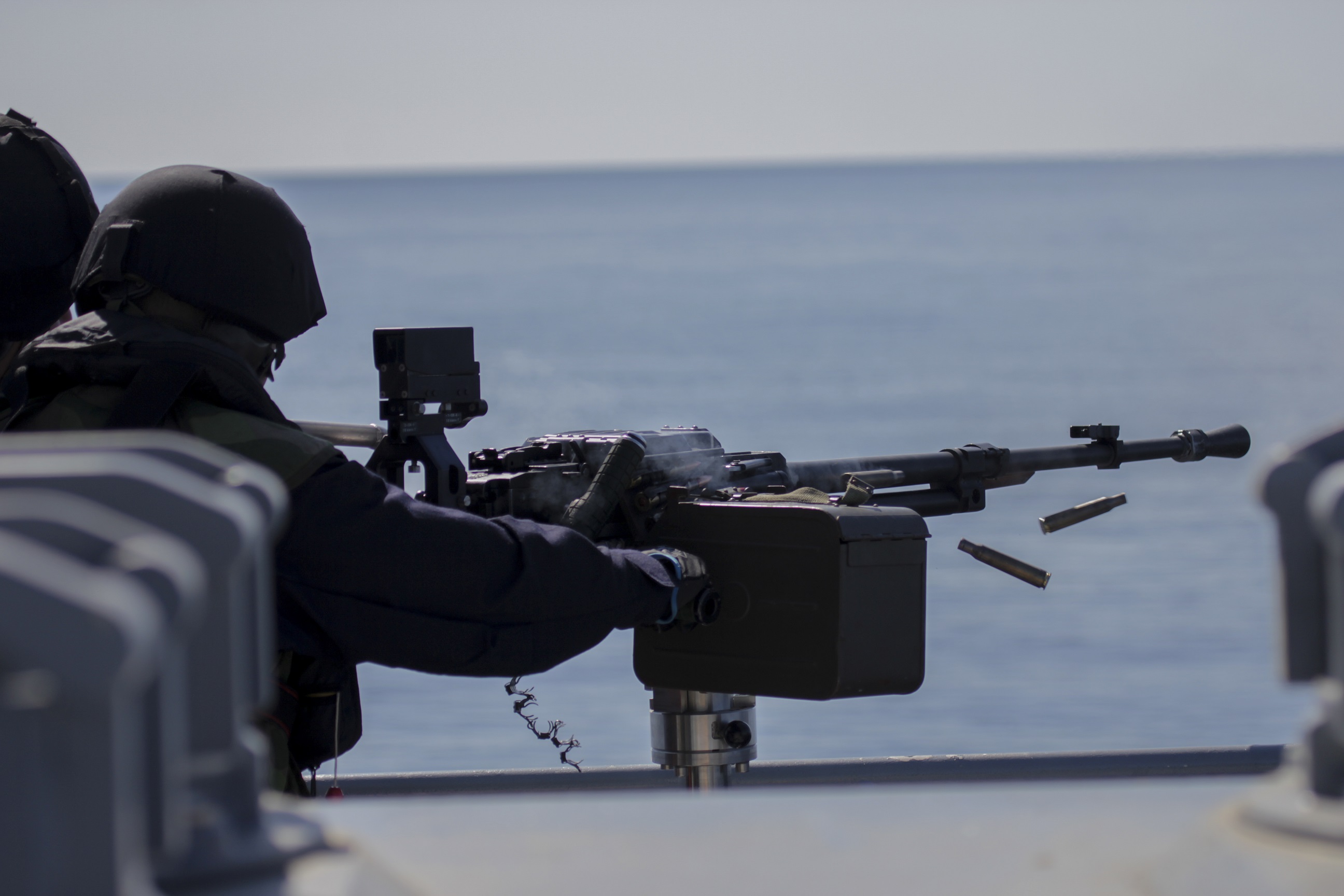 Sotilas ampuu ilmatorjuntakonekiväärillä laivan kyydistä