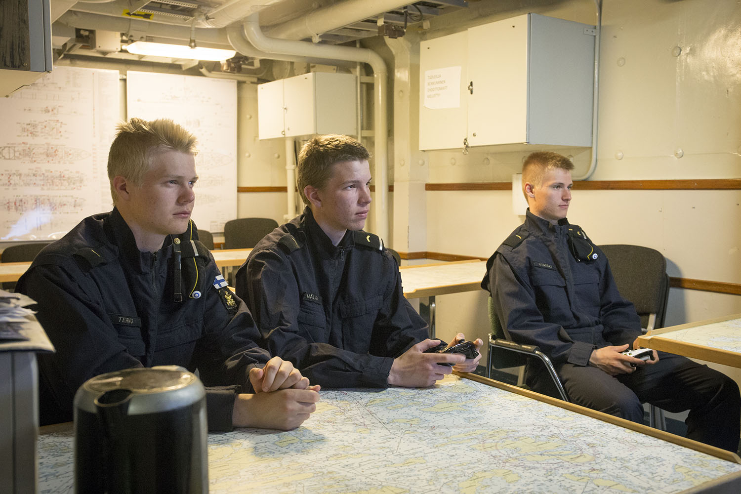 Kolme oppilaskorpraalia istuu taukotilassa ja pelaa pelikonsolilla