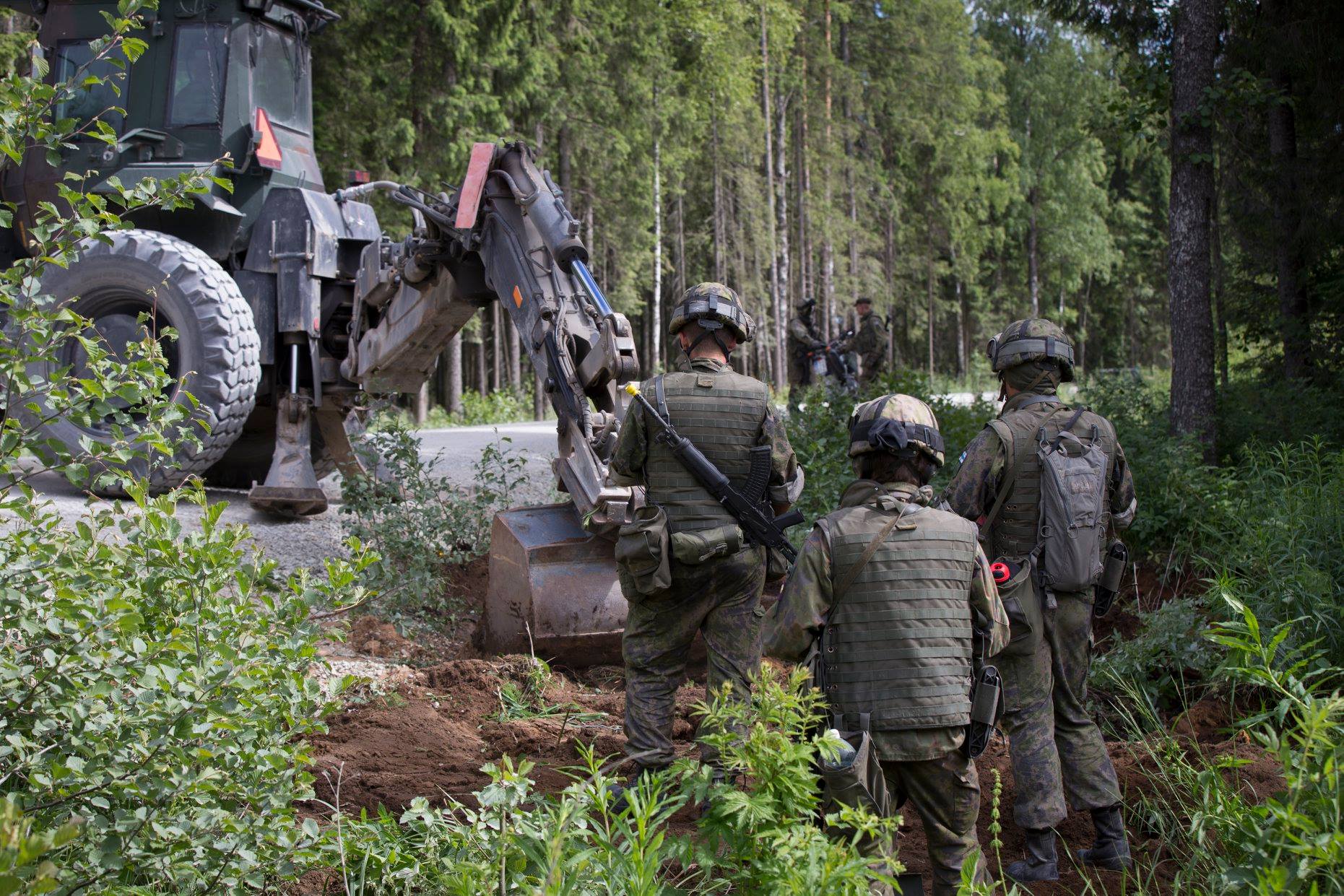 The tractor digs a pit along the road and the soldiers follow the situation