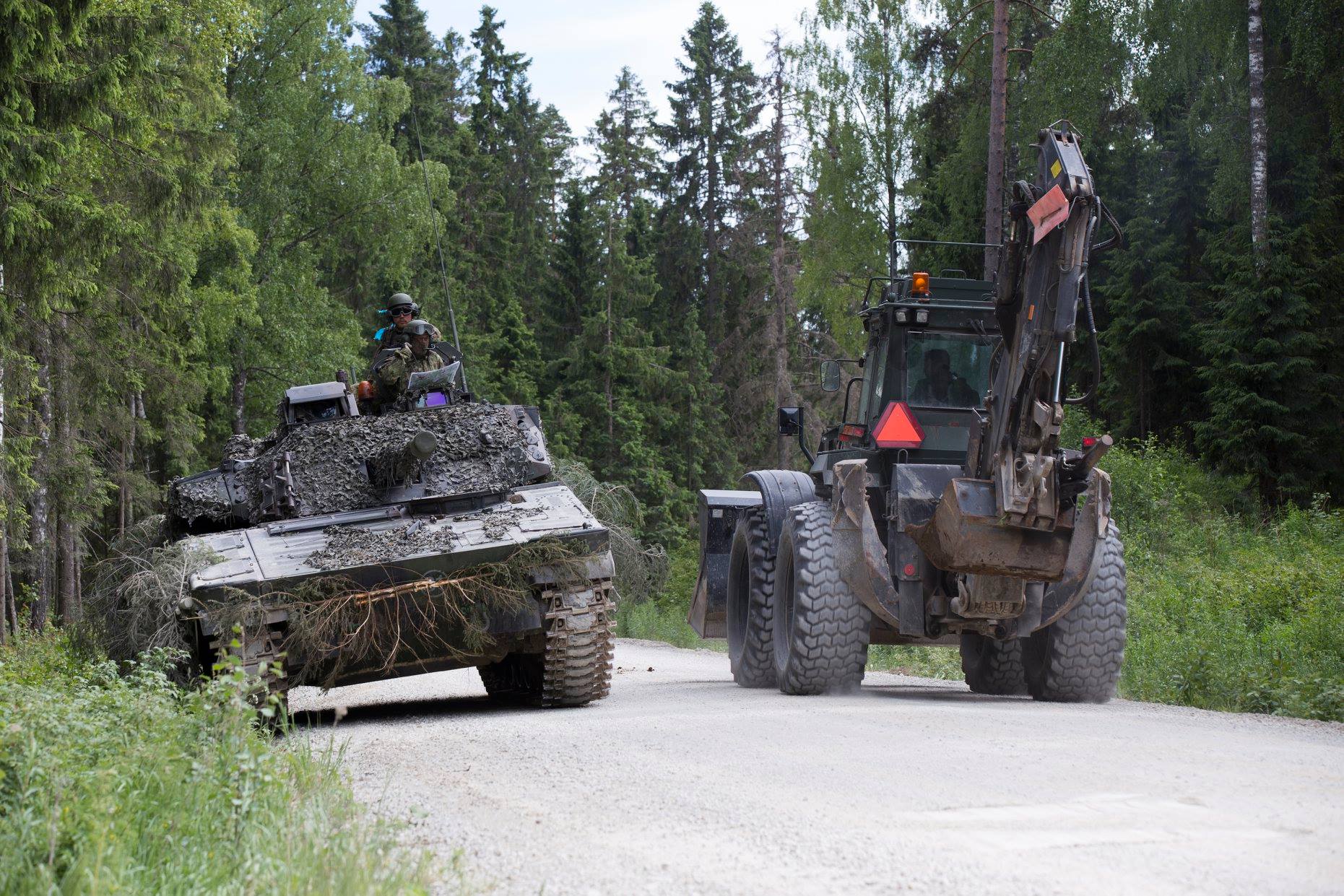 Panssarivaunu ja traktori ohittavat toisensa metsätiellä