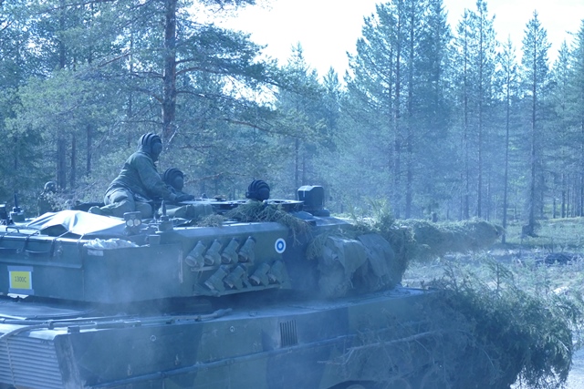 A tank with three soldiers on the roof