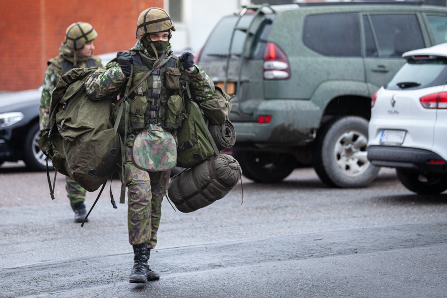 Kaksi sotilasta kantamassa varusteitaan ulkona.