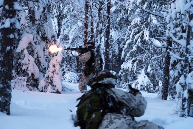 kaksi sotilasta lumisessa maastossa, toinen ampuu seisaaltaan ja toinen on maassa