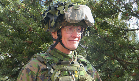 Kypäräpäinhen sotilas hymyilee ohi kameran